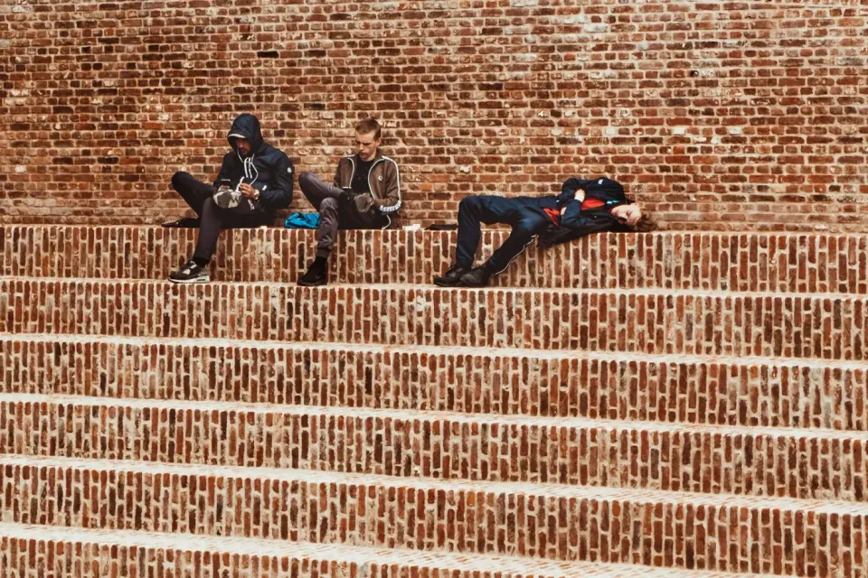Trois jeunes assis sur des gradins de brique